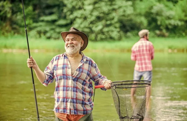 Mój połów. emerytowany dojrzały wędkarz. hobby i aktywność sportowa. ojciec i syn łowią ryby. męska przyjaźń. nawiązywanie więzi rodzinnych. Letni weekend. dwóch rybaków z wędkami, selektywne ukierunkowanie — Zdjęcie stockowe