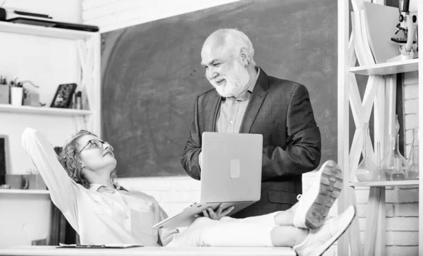 Universidad de secundaria. Comunicar clara y eficazmente. Discutiendo el tema con el estudiante o colega. Hombre maestro de escuela madura y estudiante chica despreocupada con el ordenador portátil. Escuela moderna —  Fotos de Stock