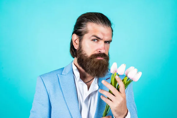 Ele gosta. Homem barbudo em roupa formal com flores de tulipa. homem de negócios elegante usar vestuário elegante para o evento formal. Presente de primavera. verdadeiro cavalheiro com buquê. conceito de data de amor — Fotografia de Stock