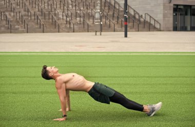 Sporcu Adam Kalas Egzersizi Yapıyor. Adam ters tahta egzersizi yapıyor. Yoga fitness adamı vücudunu tahta duruşuyla geriyor. Parkın çimlerinde ters planking egzersizi yapıyor. toplam vücut gücü