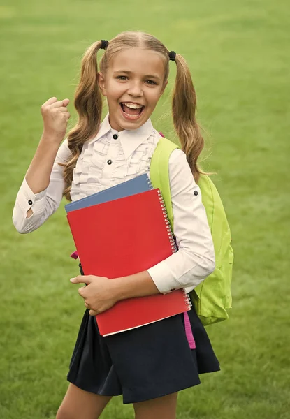 Una niña pequeña sostiene el libro. literatura para niños. desarrollo de la infancia. trabajar con cuaderno. de vuelta a la escuela. Niño con bolso escolar. niño sonriente teniendo mochila. Hagamos la tarea. Educar a todos los estudiantes — Foto de Stock