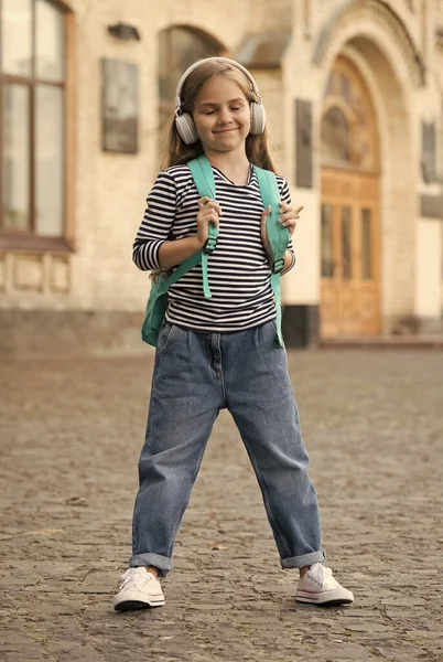Criança feliz gosta de ouvir música tocando em fones de ouvido modernos com olhos fechados em estilo casual moda urbana ao ar livre, infância — Fotografia de Stock