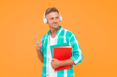 Ses kursları. İngilizce öğreniyorum. Modern teknoloji. Ses kitabı konsepti. Dünya çapında bilgi erişimi. Ses kütüphanesi. Yakışıklı öğrenci kulaklık takıyor ve kitap tutuyor. Dil çalış. Boş kurslar