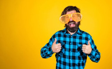 Vahşi adam kareli gömlek giyiyor. Bıyıklı erkek eğleniyor. Yakışıklı hippi partisi müdavimi. Olgun bir adamın baş parmağını göstermesi. kopyalama alanı. Komik gözlüklü sakallı adam. Gelmiş geçmiş en iyi parti