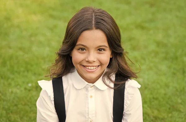 Ella es tan linda. Feliz infancia. de vuelta a la escuela. Una niña pequeña usa uniforme escolar. belleza y moda. hermosa estudiante adolescente chica en parque. lindo sonriente confiado colegiala relajarse en verde hierba — Foto de Stock