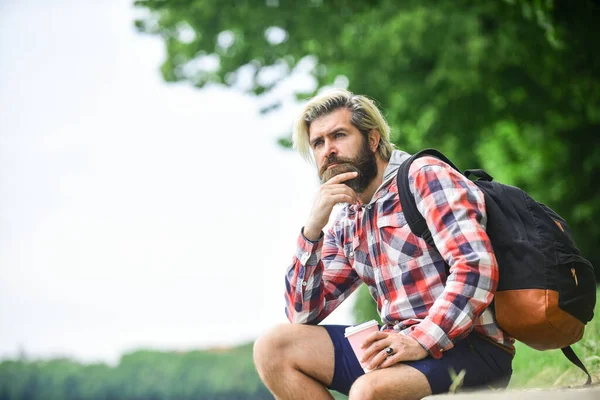 Cara hipster barbudo vestindo roupas casuais gosta de relaxar no fim de semana. conceito de bebidas matinais. estudante em coffee break. homem barbudo bebendo café enquanto sentado ao ar livre. espaço de cópia — Fotografia de Stock