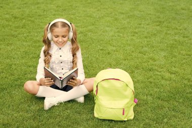 Öğrenmek için harika bir yer. Küçük kız kitabı tutuyor. Çocuklar için edebiyat. Çocukluk gelişiyor. Defterle çalış. Okula dönüyorum. Çocuk parkta ders çalışıyor. Kitapla birlikte yeşil çimlerin üzerinde rahatla. çevrimiçi müzik dinlemek