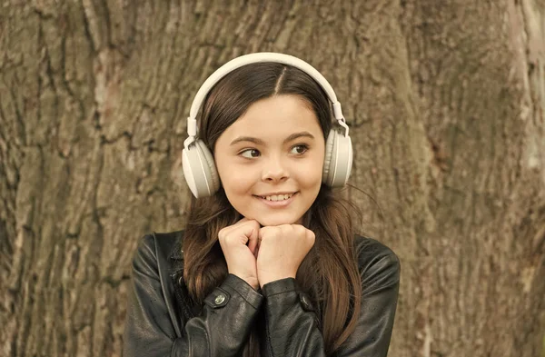 Bara musik som betyder nåt. Glad tjej lyssnar på musik utomhus. Små barn bär hörlurar som spelar musik. Konsert och musikföreställning. Ny teknik. Det moderna livet. Kul och underhållning — Stockfoto