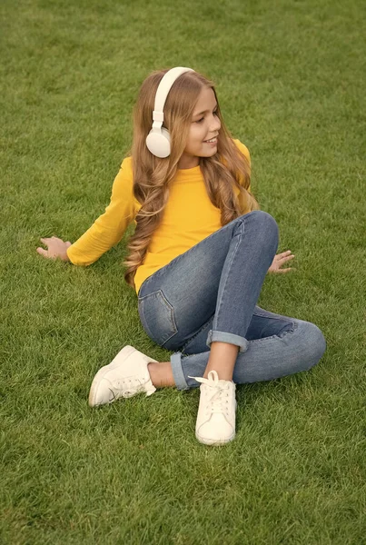 sounds of nature. relax on green grass. spring leisure time. happy childhood. kid in headset. happy little girl listen favorite song. kid beauty and fashion. teen girl listen music. education concept