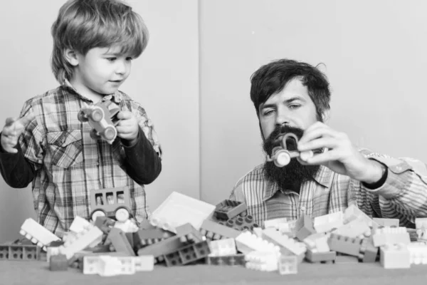 子供の発達と養育。父と子には楽しみがある。髭を生やしたヒップスターとボーイが一緒に遊ぶ。父と子供はプラスチックブロックを作る。一緒に遊ぶことの重要性。育児の概念。幸せな家族 — ストック写真