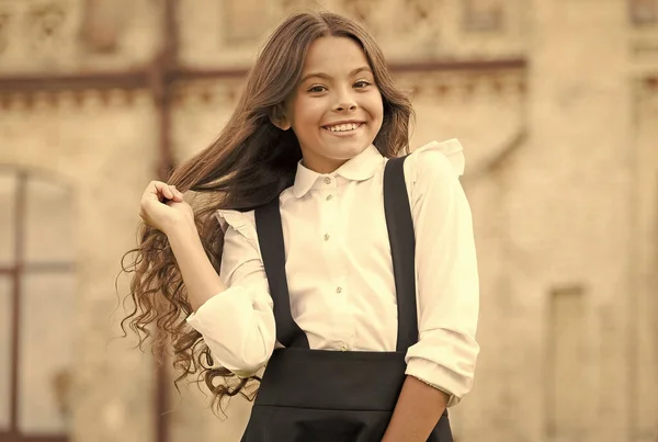 Freude an den Details. Mädchen hat lockiges Haar. kleines Mädchen trägt schicke Uniform. zurück zur Schule. moderne Bildung. Schüler auf dem Schulhof. Frühlingsferienzeit. Kind in der Schulpause. Mode und Schönheit — Stockfoto