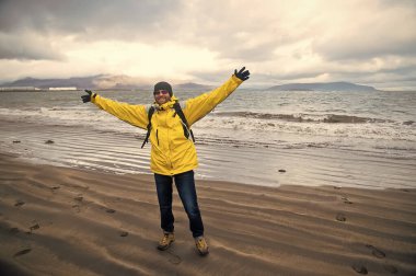 Reykjavik, İzlanda 'daki sahilde mutlu bir adam. Gezgin adam deniz kıyısında kollarını kaldırarak gülümsüyor. Özgürlük ve mutluluk. Seyahat ve seyahat tutkusu ile tatil