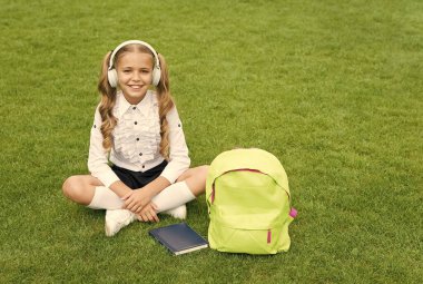 Küçük kız kitabı tutuyor. Çocuklar için edebiyat. Çocukluk gelişiyor. Defterle çalış. Okula dönüyorum. Çocuk parkta ders çalışıyor. Kitapla birlikte yeşil çimlerin üzerinde rahatla. çevrimiçi müzik dinlemek