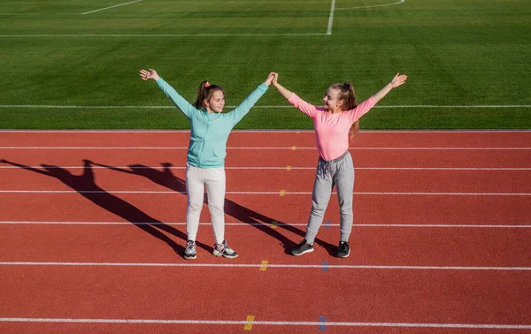 Os esportes realmente fortalecem a amizade. Os amigos felizes dão as mãos na pista de atletismo. Conceito de amizade — Fotografia de Stock