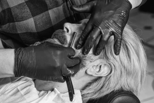 Aseo de hombre de verdad. Estilo de vida. maestro peluquero hace el peinado y el peinado con secador. Concepto Barbería. Un joven hipster con barba se cortó el pelo en una barbería. Trabajo profesional de peluquería — Foto de Stock