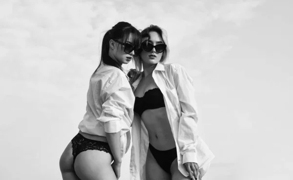 Chicas sensuales tiene una piel corporal perfecta. culo de lujo. Amor. lesbiana abrazando al aire libre. depilación y depilación. concepto de relación lgbt. salud y belleza femenina. mujeres sexy en camisa masculina — Foto de Stock