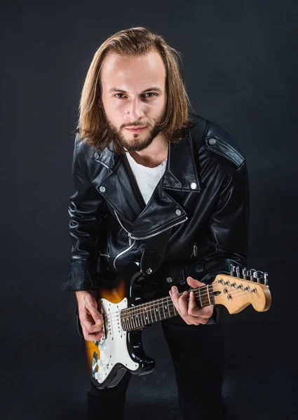 Músico de rock barbudo tocando guitarra elétrica em jaqueta de couro, baixo elétrico — Fotografia de Stock