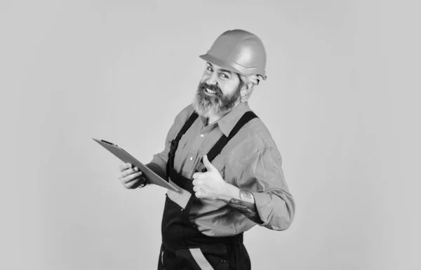 Capataz con documento. Inspeccionando. Concepto de control. Entrega de materiales de construcción. Hombre con sombrero duro sujetando portapapeles buscando información. Comprar materiales para la renovación. Un tendero barbudo. Lista de comprobación —  Fotos de Stock