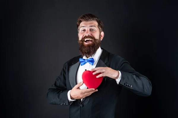 Bonito homem no smoking segurando amor presente de coração para dia dos namorados, valentine — Fotografia de Stock