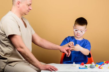 Babası hastanede olan küçük bir çocuk. Baba oğul tıp üniforması giyiyorlar. Babası steteskoplu mutlu bir çocuk. Aile doktoru. İlaç ve sağlık. Hastane konsepti. Aile hastanede.