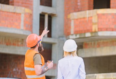 Planı tartışıyoruz. Kadın mühendis ve inşaatçı inşaat alanında iletişim kuruyor. İnşaat müşterileri ve inşaat endüstrisi arasındaki ilişkiler. İnşaat ekibi iletişim konsepti