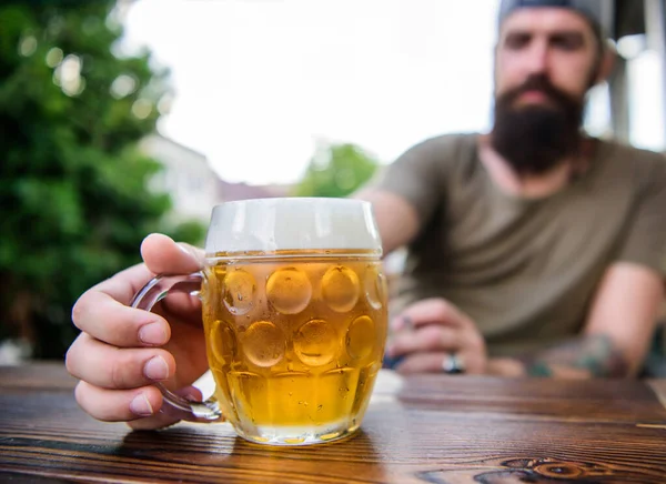 Conceito de álcool e bar. Criativa jovem cervejeira. A cerveja artesanal é jovem, urbana e elegante. Cultura de cerveja distinta. Caneca de cerveja fresca fria na mesa de perto. Homem sentar café terraço desfrutando de cerveja desfocada — Fotografia de Stock