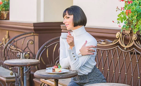 Mulher atraente elegante morena comer bolo gourmet café terraço fundo. Tempo agradável e relaxamento. Delicioso bolo gourmet. Menina relaxar café com sobremesa bolo. Conceito gourmet. Ela adora doces. — Fotografia de Stock