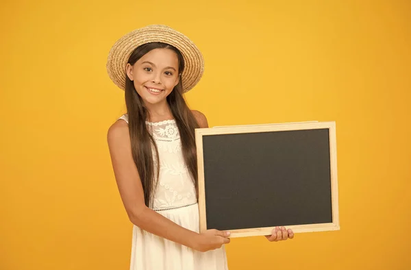 Looking trendy. travel to warm countries. kid spring fashion. girl in straw hat. advertisement. kid traveler . summer shopping sales. happy little girl hold blackboard. copy space. Hot vacation time — Stock Photo, Image