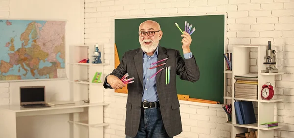 Людина використовує багато офісних інструментів. старший вчитель тримає барвистий набір ручок. виберіть будь-який колір. щасливий бородатий шкільний вчитель. повернутися до школи. клас з дошкою. шкільне написання предметів покупки — стокове фото