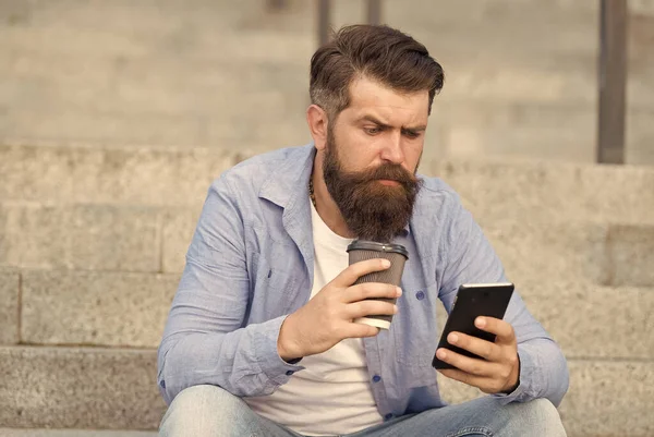 Descansa, bebe un poco de café. Hipster sostiene la taza para llevar y el teléfono inteligente. Descanso. Descanso. Descanso durante el día. Cada momento tiene su sabor — Foto de Stock