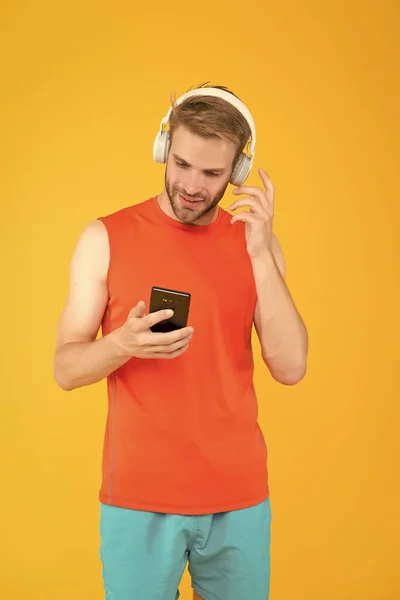 Heureux jeune homme athlète en vêtements de sport et casque écouter de la musique de playlist téléphone tout en exerçant, la créativité — Photo