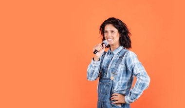 Mikrofonlu çekici bir güzellik. insan duygularını ifade etmek. Kadın müziğe şarkı söylüyor. Mutlu kadın mikrofonda şarkı söyler. Kareli gömlekli ve kot pantolonlu kız şarkıcı. Komik parti meraklısı. Boşluğu kopyala