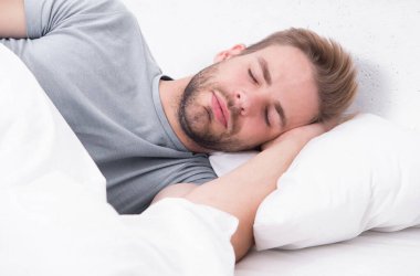 Derin bir uykuda kaybolmuş. Uykucu sabahları uyumaktan zevk alıyor. Yatakta uyuyan yakışıklı adam. Sabah onu uyandırma. Daha fazla uykuya ihtiyacı var.