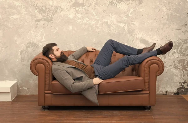 Мужчина расслабляется на роскошном кожаном диване, чувствуя себя комфортно — стоковое фото