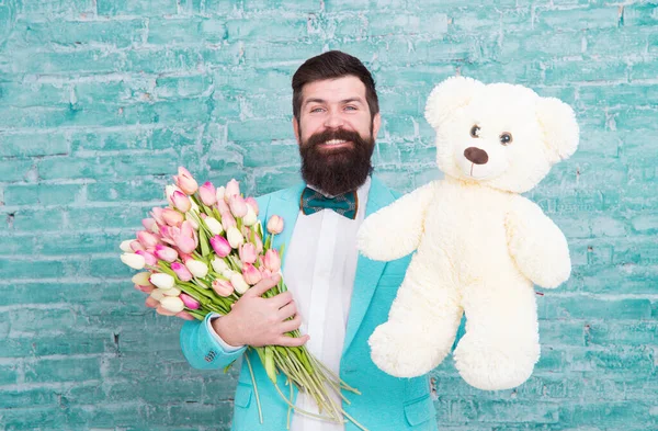 Macho se preparando encontro romântico. Homem usar azul smoking arco gravata segurar flores buquê. Dia Internacional da Mulher. A surpresa vai derreter-lhe o coração. Homem romântico com flores e ursinho. Presente romântico — Fotografia de Stock