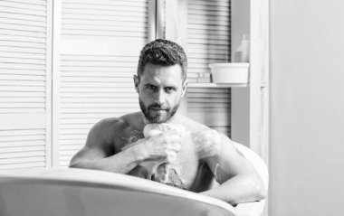 Deri bakımı konsepti. Sabun köpüğüyle banyo yapmak. Kendini sıcak ya da sıcak bir banyoyla şımartmak lüksün doruk noktasındaymış gibi hissettirebilir. Şımartma ve güzellik rutini. Banyoda rahatlayan yakışıklı kaslı adam.