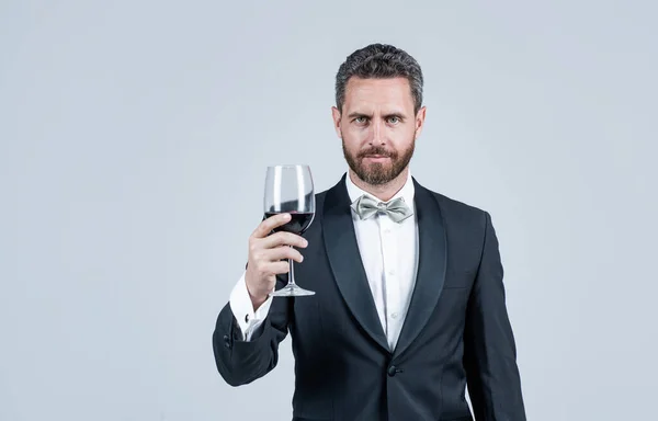 Guapo esmoquin hombre vítores con copa de vino tinto celebrar caja de regalo detrás, espacio de copia, sommelier — Foto de Stock