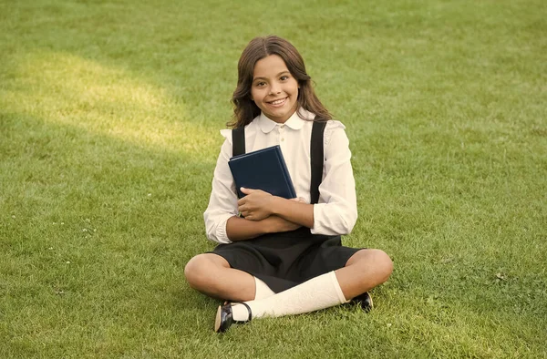 Dospívající dívka s knihou o zelené trávě. hezká holčička čte knížku. studovat literaturu pro děti. Bavit se s knihou. Den znalostí. moderní školní vzdělání. šťastné dětství — Stock fotografie