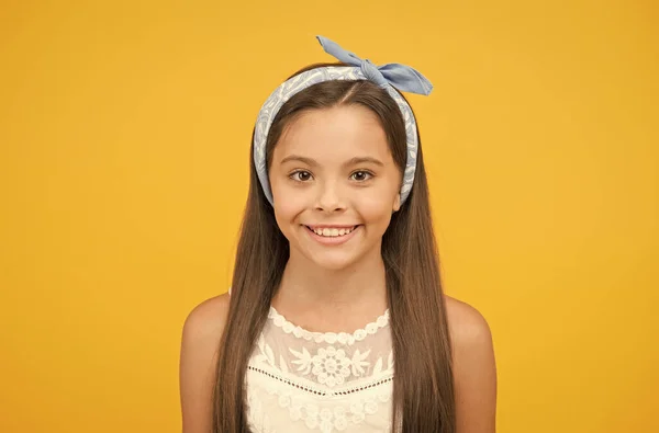 Lindo a cada momento. Menina feliz criança fundo amarelo. Criança pequena com sorriso bonito. Criança usa cabelos longos e morena. Salão de beleza. Moda e estilo. Cuidados infantis e infância. Dia das crianças — Fotografia de Stock