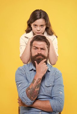 Baba her çocuğun idolüdür. Küçük kız babaya sarılıyor. Küçük kız ve baba sarı arka plan. Babalar Günü. Aile değerleri. Baba biz asla ayrılmayacağız.
