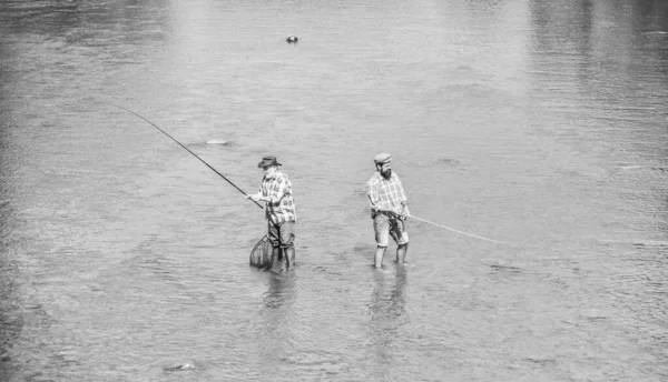 Qui va gagner. hobby et activité sportive. Un appât à truites. Pêche au gros. amitié masculine. loisirs et loisirs de plein air. deux pêcheurs heureux avec canne à pêche et filet. pêche père et fils. aventures — Photo