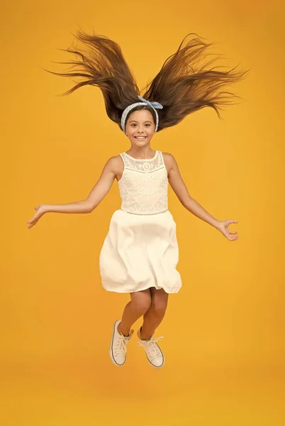 Salon that brings your hair to the next level. Happy child jump yellow background. Small girl with long brunette hair. Hair salon. Beauty salon. At hairdressers. Salon care for every haircare need — Stock Photo, Image