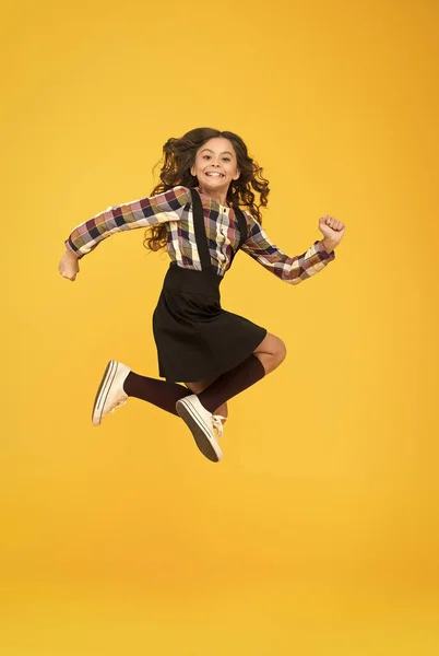 Čas na zábavu. Aktivní dívka cítí svobodu. Zábava a skok. Šťastný dětský den. Koncept skoku. Vloupat se dovnitř. Cítit vnitřní energii. Dívka s dlouhými vlasy skákání na žlutém pozadí. Bezstarostné dítě letní dovolená — Stock fotografie