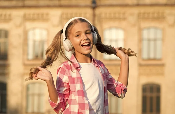 Inspirado pela música favorita. menina pequena ouvir música. Um miúdo com auscultadores. felicidade infantil. criança feliz no humor brincalhão tem cabelo loiro. penteado bonito e elegante. tempo de lazer na primavera — Fotografia de Stock