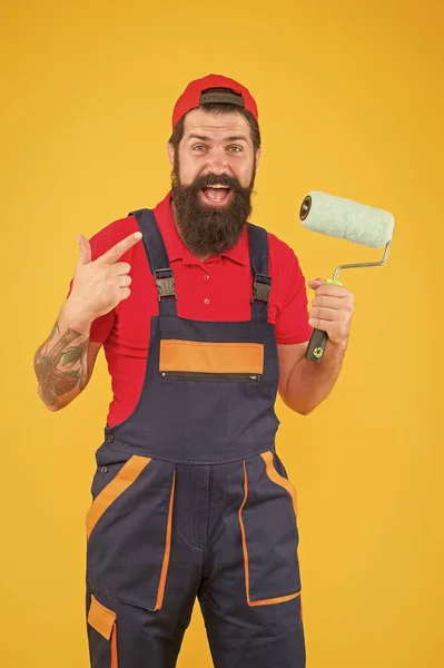 O capataz vai fazer a parede virada. homem brutal feliz em uniforme de fato-calça. hipster maduro usar ferramenta rolo de pintura para pintura. reparador ou construtor trabalhando. ideia criativa — Fotografia de Stock