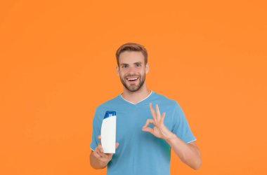 Kişisel bakım. Mükemmel banyo terapisi. Arkadaş canlısı tezgahtar. Mutlu adam şampuan şişesini tutuyor. Saçını köpükle yıkayan adam. Kuaför ve berber dükkanı. Tıbbi nemlendirici jel reklamı