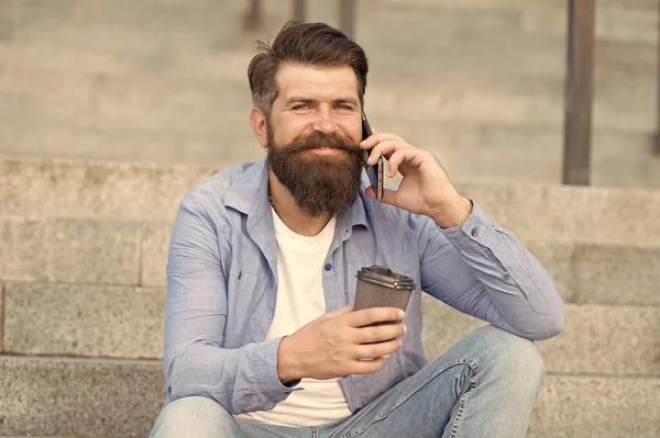 Una pequeña charla con alguien. Feliz hipster beber café hablando por teléfono al aire libre. Haciendo una llamada. Conexión de celular. Nueva tecnología. La vida moderna. El teléfono móvil facilita la comunicación — Foto de Stock