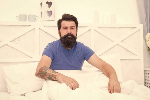 Relajado se despertó hombre con bigote sentarse en la cama después de dormir, la paz de la mañana —  Fotos de Stock