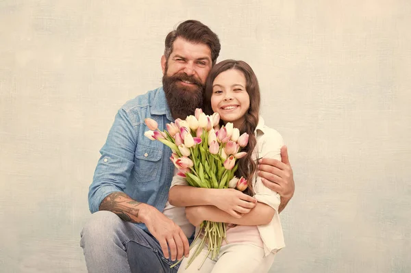 Šťastný rodinný den. otec a dcera se obejmou s květinami. teen holka a táta drží tulipánovou kytici. 8. března nebo ženský den. Dárek na jarní dovolenou. láska a rodinné hodnoty. štěstí — Stock fotografie