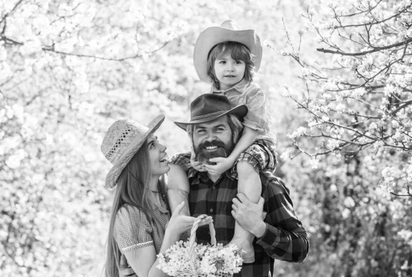 Agriculteurs dans le jardin fleuri. Les parents grandissent petit bébé. Passez du temps ensemble. Belle famille en plein air fond de nature. Concept de ranch. Bonne journée en famille. Mère père et mignon fils. Ferme familiale — Photo